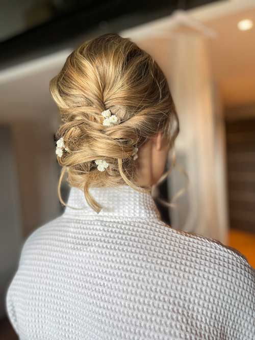 Blond tjejs håruppsättning med vita blommor